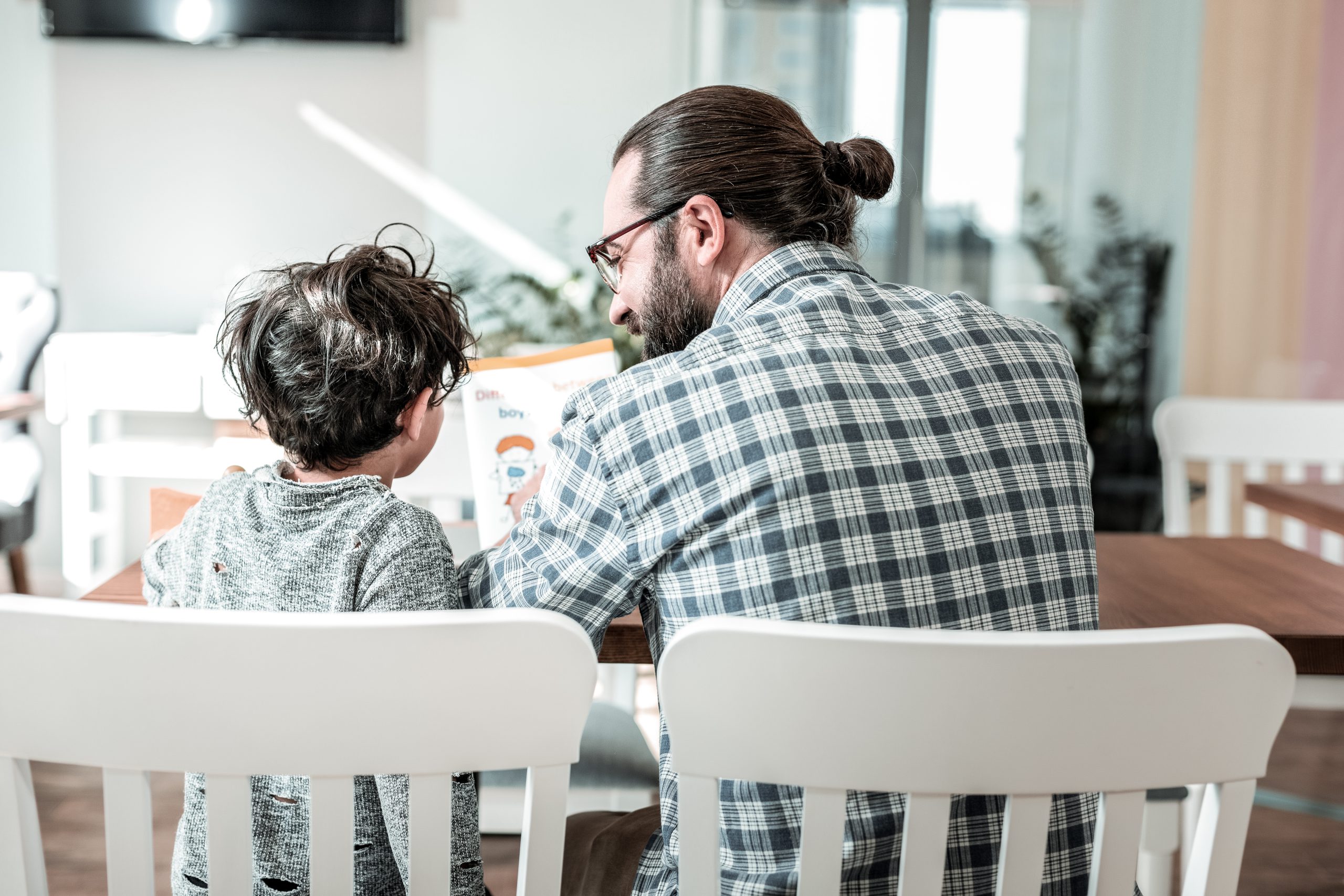 Father and son reading the kids book waiting for their order